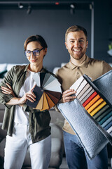 Woman and man designer with textile swatches and wooden palette at furniture store
