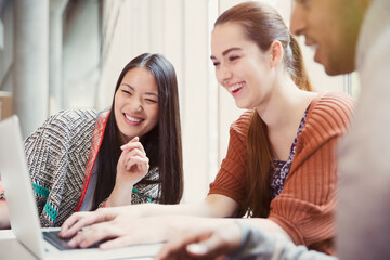 Smiling college students using laptop