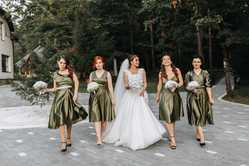 Beautiful bride and her friends- bridesmaids having fun after wedding ceremony. Happy girls at their best friend's wedding. Beautiful and elegant bride with bridesmaids walking on the stairs