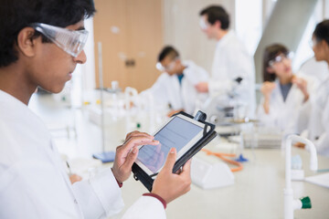Male college student using digital tablet in science laboratory classroom