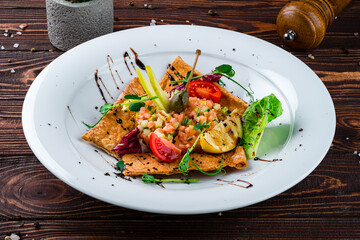 Fresh salmon tartare with cucumbers, toasted bread, capers, tomatoes, lettuce and sauce.