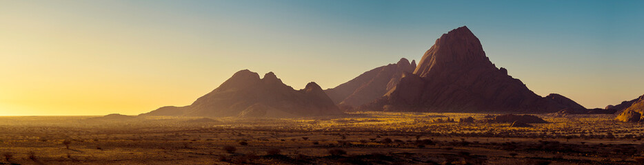 Mountain landscape of Spitzkoppe peaks on sunrise, panorama of a stone desert in morning soft light, Namibia. Travelling and adventures to wildlife.