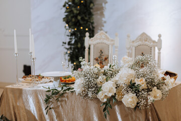 Wedding table serving. Wedding luxury decor. Wedding presidium for the newlyweds. Beautiful decor with pastel roses, candles and greenery. Indoors