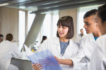 College students discussing notes in science laboratory classroom