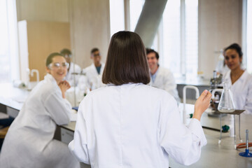 Female college student leading study group in science laboratory classroom