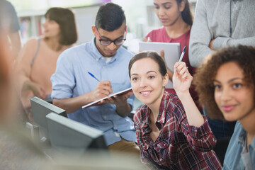 College student raising hand in computer lab classroom