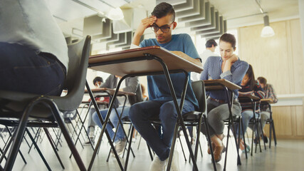 College students taking test at desk in classroom