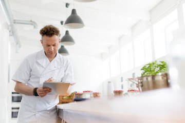 Chef teacher preparing with clipboard in cooking class kitchen