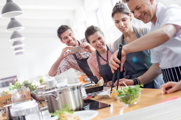 Students watching chef teacher in cooking class kitchen