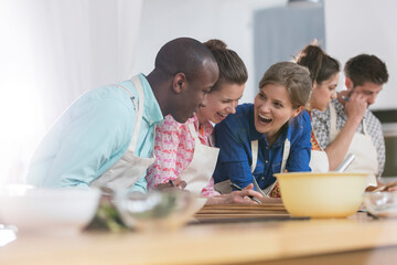 Laughing friends enjoying cooking class in kitchen