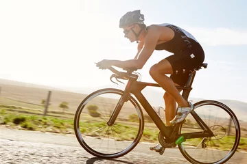 Foto auf Glas Male triathlete cyclist cycling on sunny rural road at sunrise © KOTO