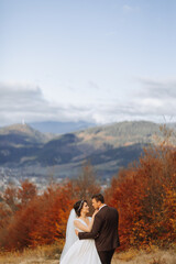 Loving couple in the mountains. Weddings in the mountains. Back view of the newlywed couple standing on the mountains and enjoying the landscape.