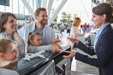 Customer service representative helping family checking in tickets at airport check-in counter
