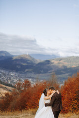 Loving couple in the mountains. Weddings in the mountains. Back view of the newlywed couple standing on the mountains and enjoying the landscape.