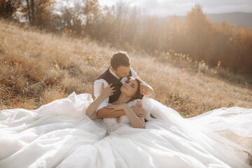 portrait of a stylish groom with a bride on a background of autumn dry grass. the concept of a...