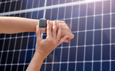 Smartwatch on female hand on background of solar energy panel. remote control of home solar energy station.