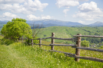 Fototapeta na wymiar wooden fence in the mountains of the Carpathians against the backdrop of a green meadow