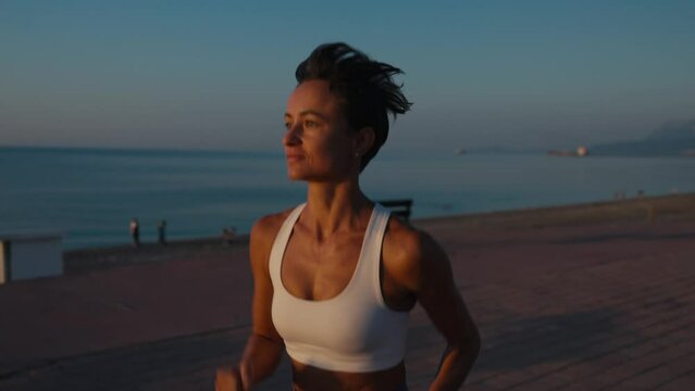 Young fitness sport woman running on road at sunset. Athlete runner feet running on road, slow motion. High quality 4k footage