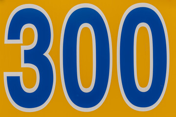 300 foot ft baseball field distance sign in yellow and blue mounted on the outfield fence.	