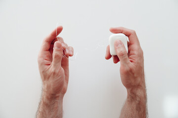 Man's hands holding dental floss over white background