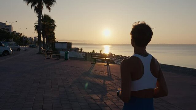 Young fitness sport woman running on road at sunset. Athlete runner feet running on road, slow motion. High quality 4k footage