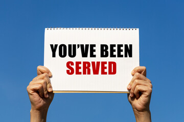 You've been served text on notebook paper held by 2 hands with isolated blue sky background. This...