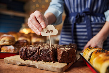 Sales Assistant In Bakery Putting Vegan Label Into Freshly Baked Chocolate Brownies