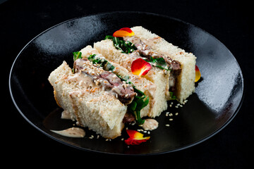 Sandwich with beef, lettuce, sauce and sesame seeds, appetizer.