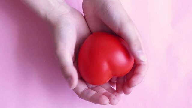 Children's hands holding a red heart as a simbol of care, love, support and protection