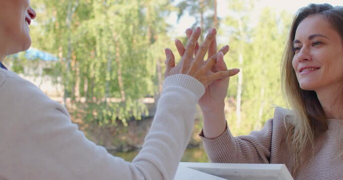 Feel the deep connection of human touch as the hands of a female couple lightly touch each other, gently intertwining their fingers. The power of touch in creating connections. Zoom in 4k footage.