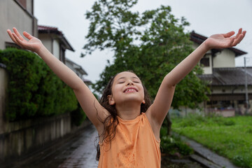 Joyful girl smiles charmingly and holds out her hands to the sky. 