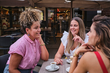 three friends drinking coffee and chatting on a terrace