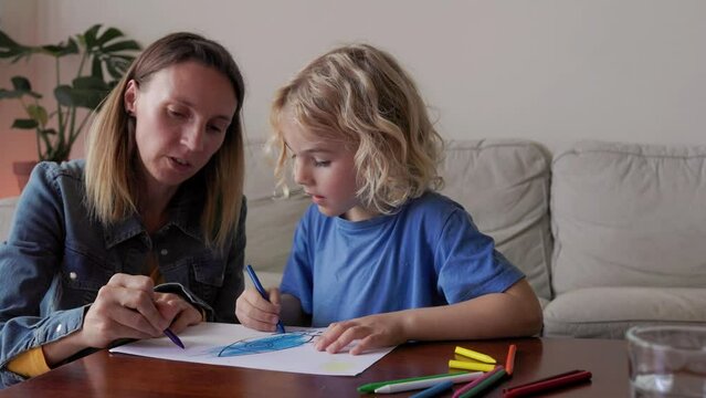Mother and son child drawing together having fun inside home living room