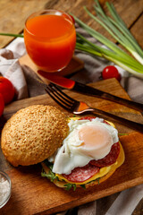 Wooden board with tasty egg Benedict on table