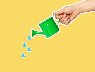 Hand holding a small green watering can and blue water drops on yellow background, art collage, cut out style. © Barillo_Images