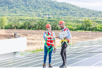 Obraz premium Professional technicians carrying photovoltaic solar moduls on factory roof, Engineers in helmets installing solar panel system outdoors. Concept of alternative and sustainable renewable energy.