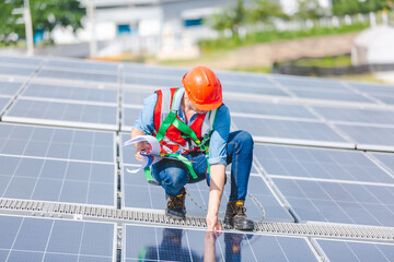 Professional worker cleaning solar panels with brush and washing with water on roof structure of...