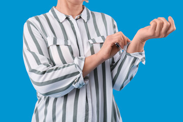Mature woman rolling up her sleeve on light blue background