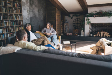 Group of aged friends resting in lounge zone while communicating