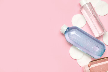 Bottles of micellar water with cotton pads on pink background © Pixel-Shot