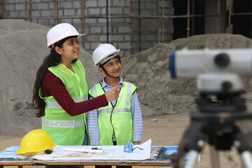 Young Indian School kids working as a role model engineer on a builder construction site working on...