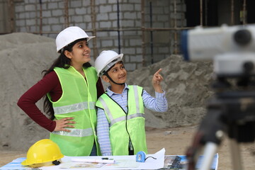 Young Indian School kids working as a role model engineer on a builder construction site working on...