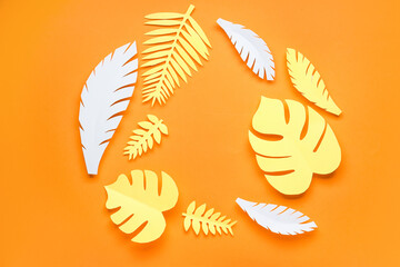Fototapeta na wymiar Frame made of paper tropical leaves on orange background