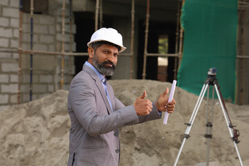 Hardworking Indian Site engineer figuring out the work in progress. On the site location wearing...