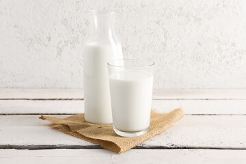 Bottle and glass with fresh milk on light wooden table