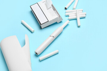 Modern electronic cigar, pack and sticks on blue background