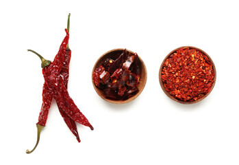 Dry chili with bowls of ground and sliced pepper on white background