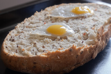 A mouthwatering capture featuring bread topped with a fried quail egg. The golden yolk adds a delightful richness to the dish. Ideal for food, breakfast, and brunch themes.