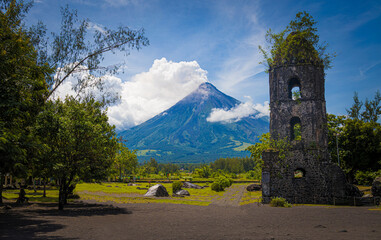 volcano in eruption next to old bell tower demolished by lava