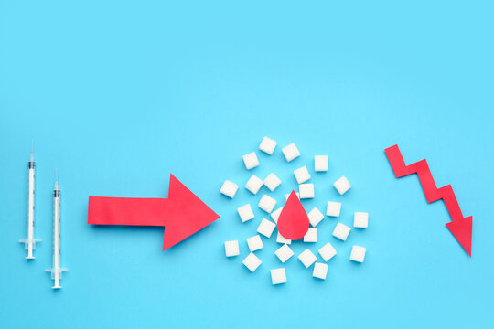 Diabetes management with syringes, sugar cubes, blood drop, and a red downward arrow on a blue background